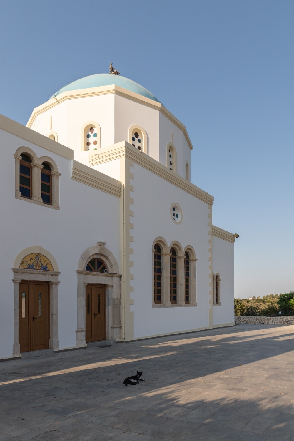 White Greek style church with a blue dome on a clear day